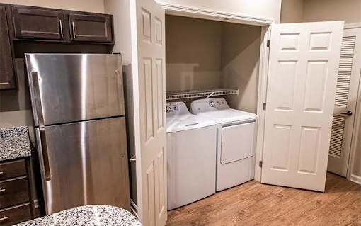A small kitchen with a refrigerator, microwave, and washing machine.