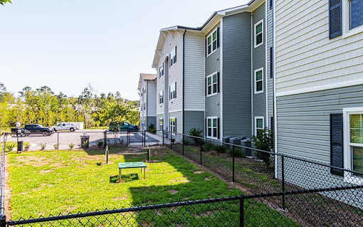 A view of a green lawn in front of a building with a fence.