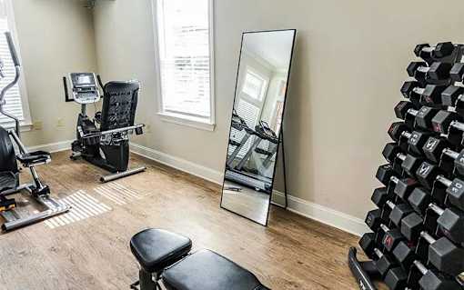 A gym room with a mirror, weights, and exercise equipment.