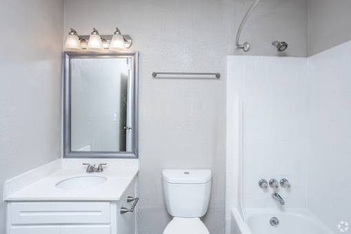 A white bathroom with a toilet, sink, and bathtub.