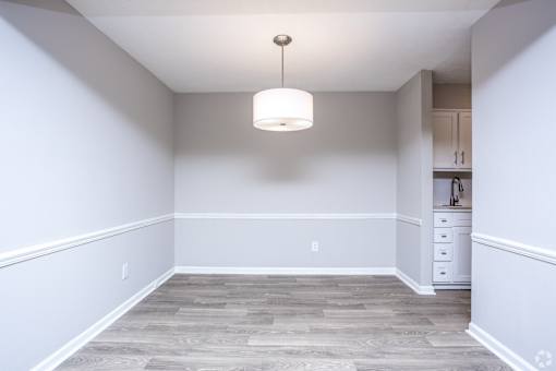 A room with a grey floor and a white ceiling with a light hanging from it.