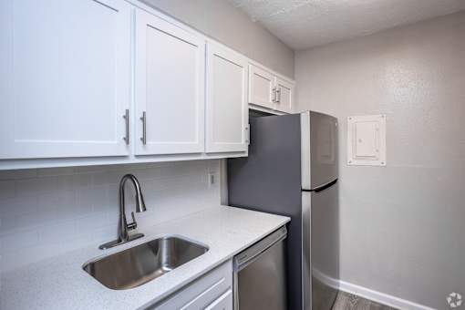 A kitchen with a sink, dishwasher, and refrigerator.