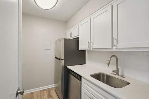 A kitchen with a black refrigerator and white cabinets.