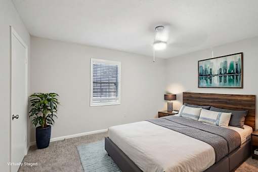 A bedroom with a bed, nightstands, and a potted plant.