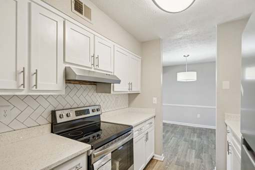 A kitchen with white cabinets and a black stove top oven.