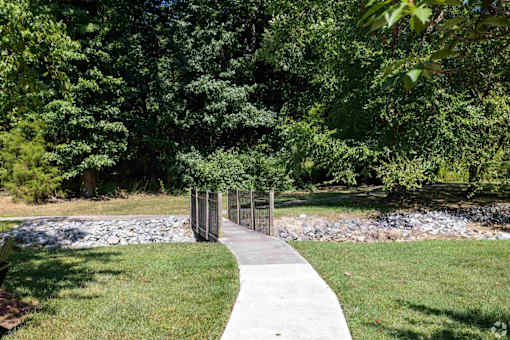 A concrete walkway leads through a grassy area to a metal gate.