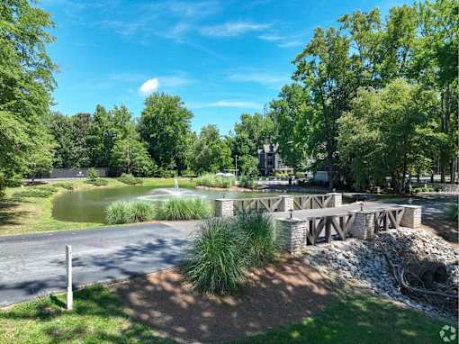 A serene park with a bridge, a pond, and lush greenery.