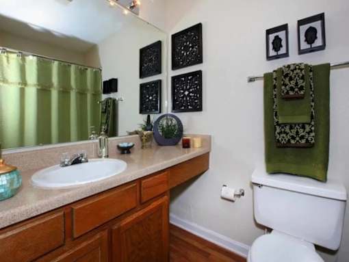 A bathroom with a white toilet, a sink, and a green towel.