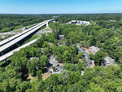 A highway runs through a wooded area with a small town in the distance.