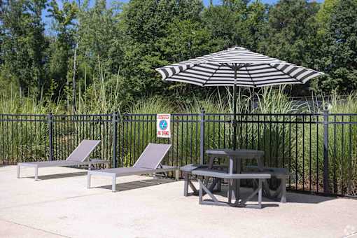 A black and white striped umbrella is in front of a fence with a sign on it.