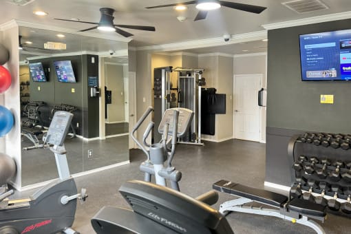 a gym with cardio equipment and a tv in a building