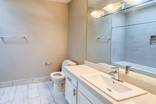 A bathroom with a toilet, sink, and mirror.