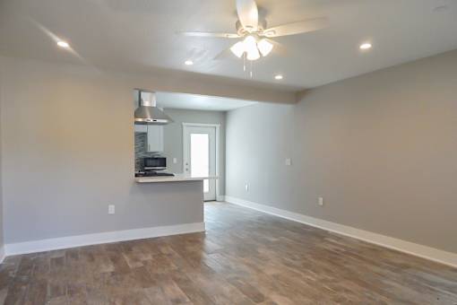 A room with a ceiling fan and wooden flooring.