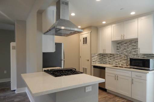 A kitchen with a white countertop and a black stove top.