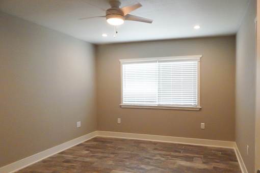 A room with a ceiling fan and a window with blinds.