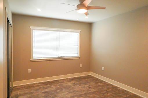 A room with a ceiling fan and a window with blinds.