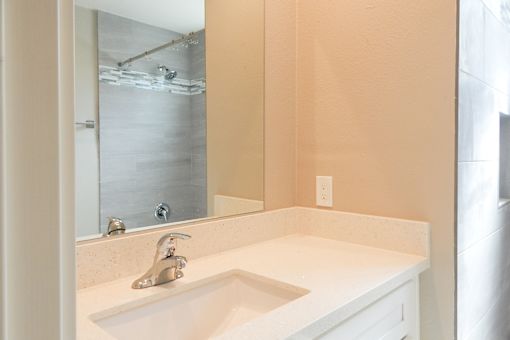 A bathroom sink with a silver faucet and a mirror above it.