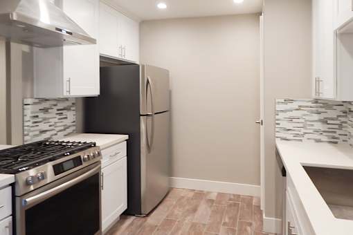 A kitchen with a black refrigerator and a stove top oven.