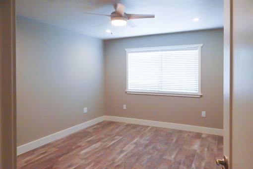 A room with a ceiling fan and a window with blinds.