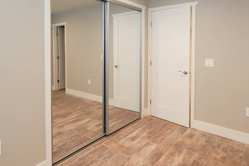 A room with a white door and a mirror on the wall.