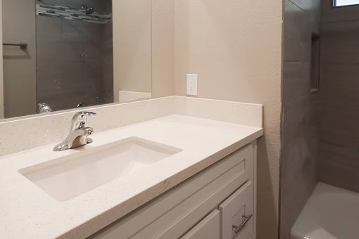 A white sink in a bathroom with a mirror above it.