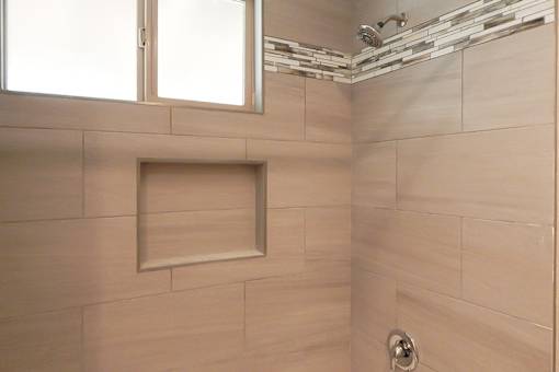 A bathroom with a tiled shower and a window.