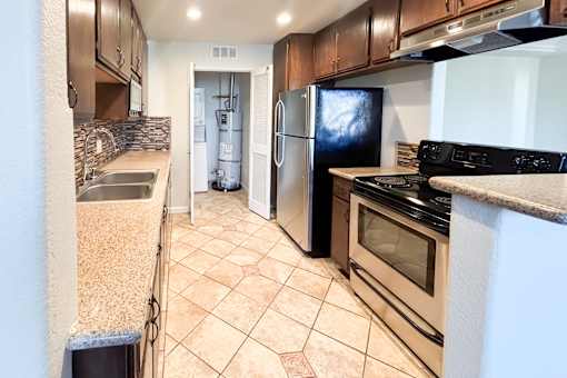 A kitchen with a black fridge and stove top oven.