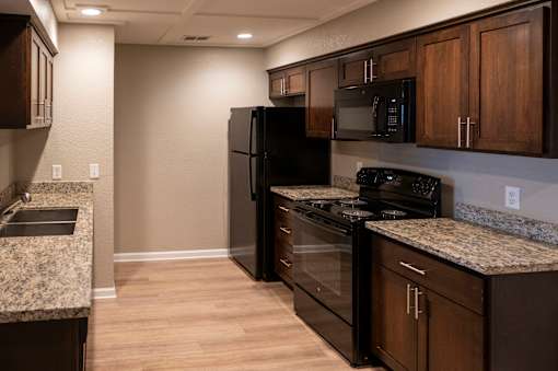 A kitchen with black appliances and wooden cabinets.