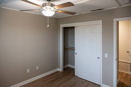 A room with a white door and a ceiling fan.