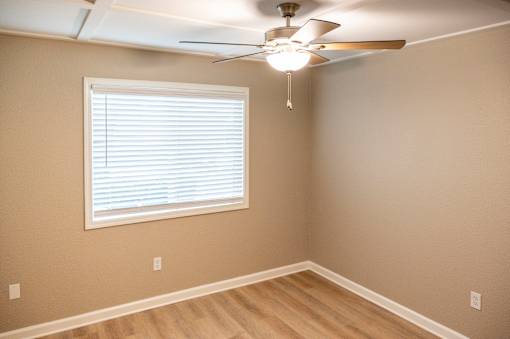 A room with a ceiling fan and a window with blinds.
