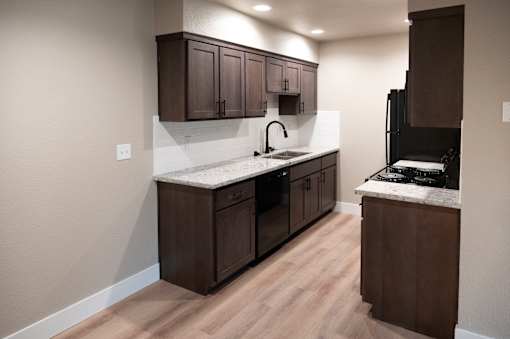 A kitchen with dark brown cabinets and a white countertop.