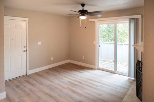 A room with a ceiling fan and sliding glass doors.