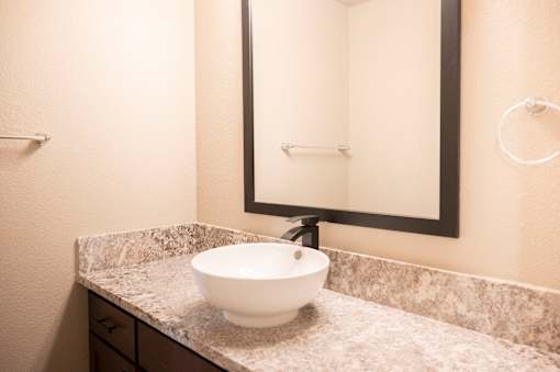 A white bowl sink is on a marble countertop.