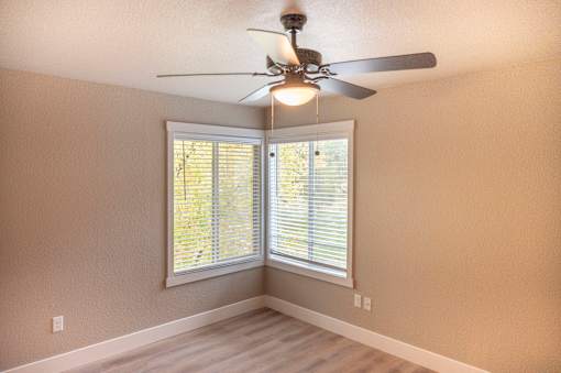 A room with a ceiling fan and a window with blinds.