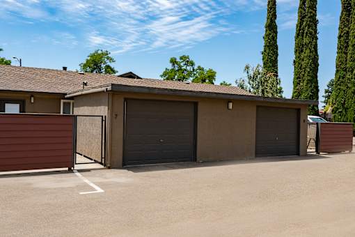 A garage with a brown door is situated in front of a house.