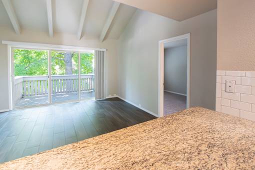 A room with a large bed and a balcony with a view of trees.