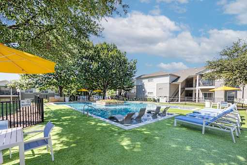 A pool area with sun loungers and a yellow umbrella.
