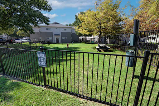 A black fence surrounds a green field with a sign that says "No Parking".