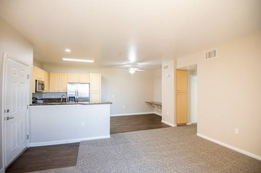 A spacious living room with a kitchen area in the background.