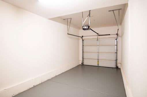 A garage with a white door and a grey floor.