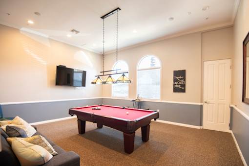 A pool table in a room with a couch and a television.