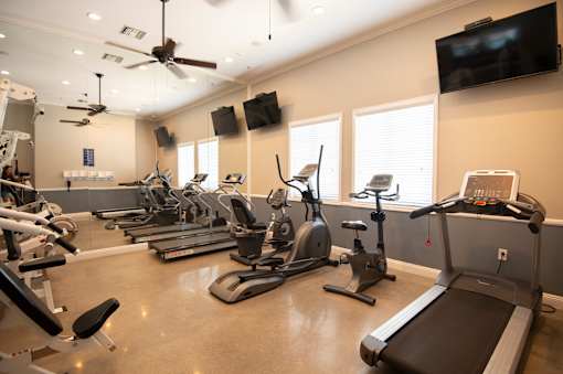 A spacious gym with treadmills, elliptical machines, and a television.