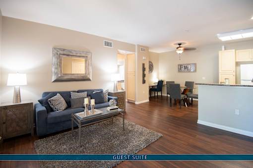 A living room with a couch, a coffee table, and a mirror on the wall.