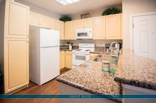 A kitchen with a white refrigerator, wooden cabinets, and granite countertops.