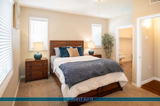 A guest suite bedroom with a large bed and two lamps.