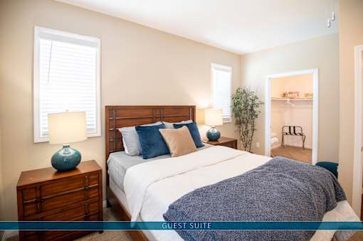 A guest suite bedroom with a large bed and a nightstand with a blue vase on it.