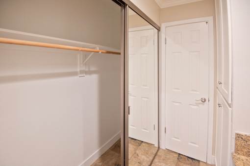 A white closet with a mirror on the door.