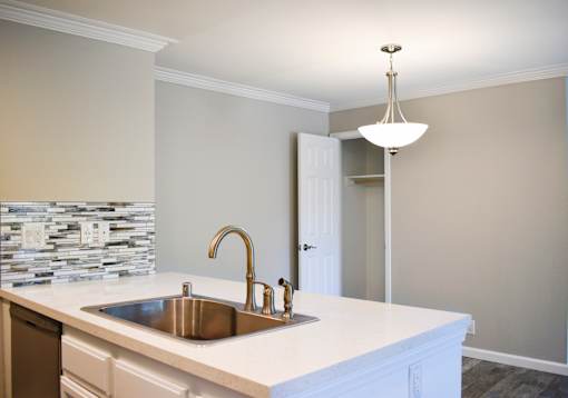 A kitchen with a white counter top and a silver sink.