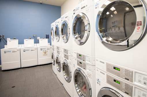 A row of white front load washing machines in a laundromat.