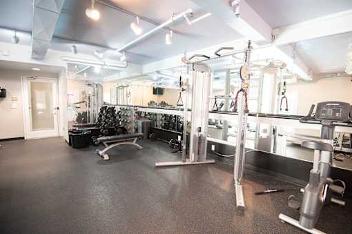 A gym with a variety of equipment including a squat rack, bench, and weights.